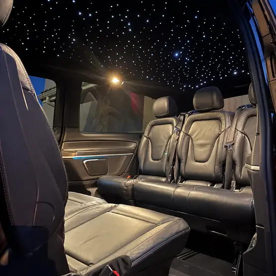 Sièges en cuir noir et plafond à éclairage étoilé dans un van.