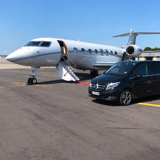 Van Mercedes noir stationné à côté d’un jet d’affaires sur le tarmac.