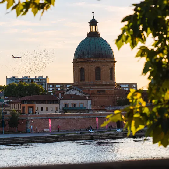 Dôme de la Grave au bord de la Garonne à Toulouse, avec un avion dans le ciel.